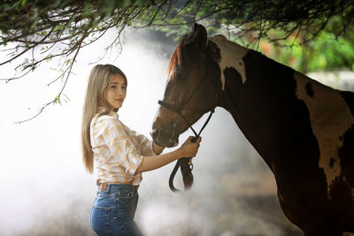 Young woman standing by horse