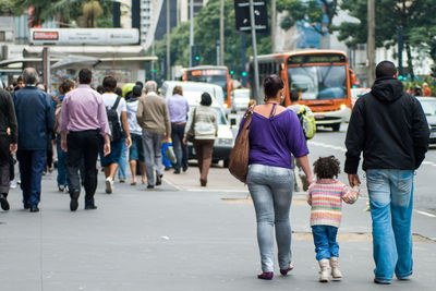 Rear view of people walking on road in city