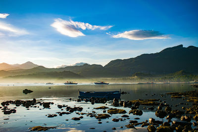 Fishing boat and stones on shallow water in calm morning