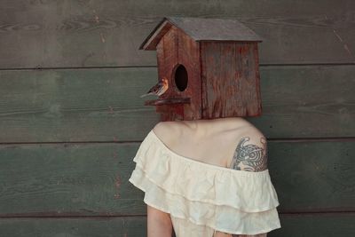 Woman wearing house with bird against wall