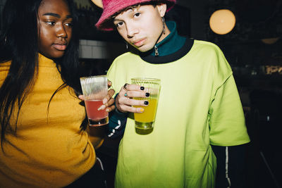 Portrait of man and woman with drinking glass standing at cafe