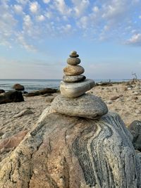 Rear view of woman standing on rock by sea against sky