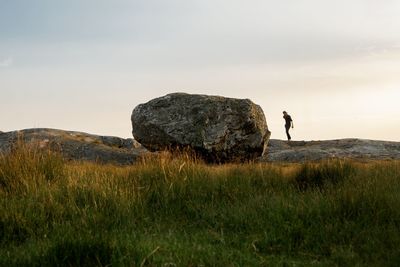 Man standing on rock against sky during sunset