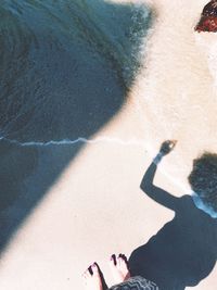 Low section and shadow of woman at beach