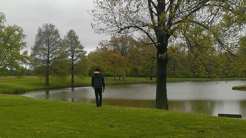 Full length of woman standing by pond