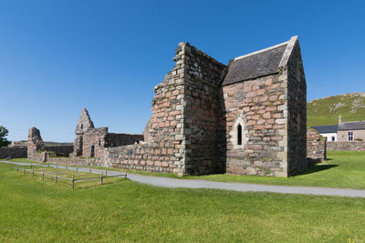 Historic building on field against clear blue sky