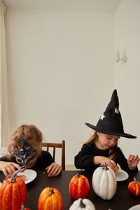 Rear view of woman with pumpkins against wall