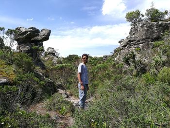Full length of woman standing on rock against sky