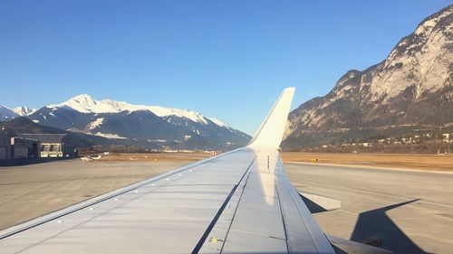 Airplane wing over mountains against clear sky