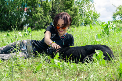 Side view of young woman sitting on grassy field