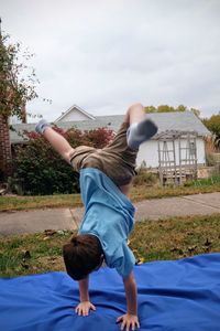 Boy doing handstand on picnic blanket in park