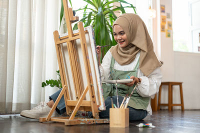 Portrait of young woman sitting on chair at home