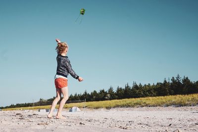 Woman jumping on beach against clear sky