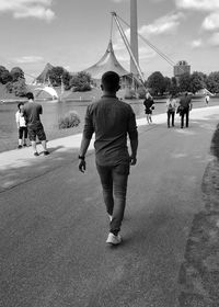 Rear view of people walking on road in city