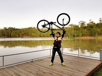 Full length of man holding umbrella by lake