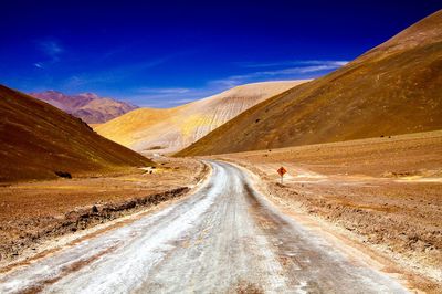 Road leading towards mountains against sky