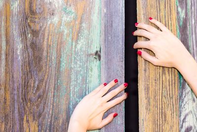 Cropped hands of woman holding wooden wall