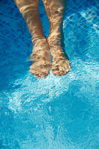 Low section of woman relaxing in swimming pool