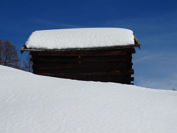 White house on snow covered field against sky