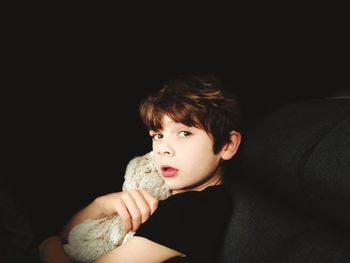 Portrait of boy holding toy against black background