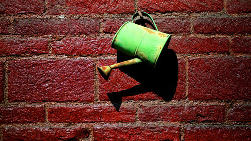 Close-up of abandoned metal against brick wall