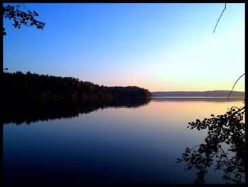 Reflection of trees in calm lake at sunset