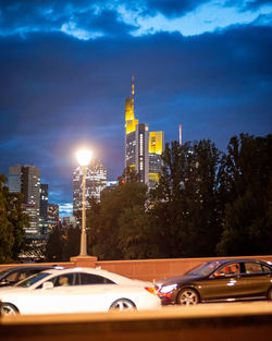 Cars on street against illuminated buildings in city