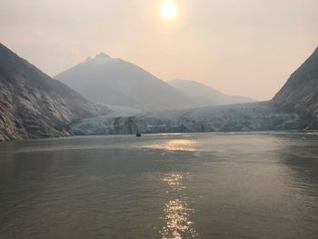 Scenic view of lake and mountains against sky during sunset