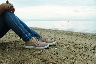 Low section of person on beach against sky