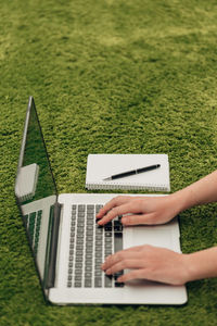 Midsection of woman using laptop on grass at park