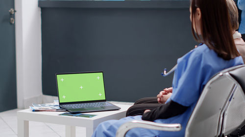 Rear view of woman using laptop at office