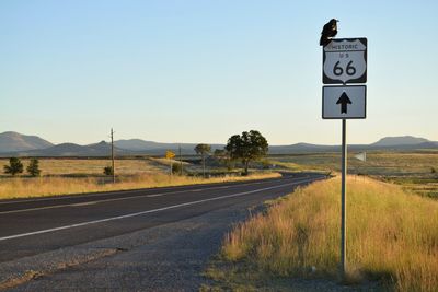 Road sign on landscape against clear sky