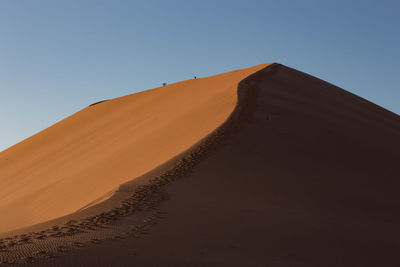 Low angle view of desert against clear blue sky