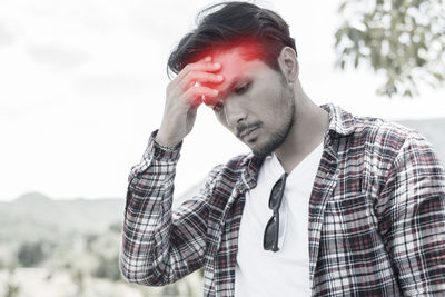 Man with headache against sky