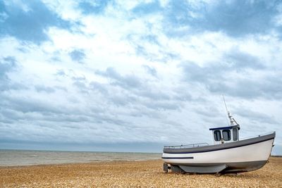 Sailboat moored on beach against sky