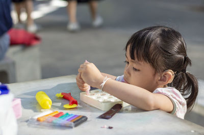 Close-up of cute girl playing with childs play clay at table outdoors