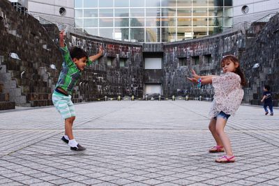 Full length of siblings dancing on street