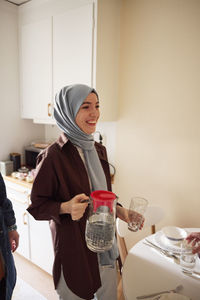 Happy woman in headscarf setting table for eid al-fitr at home