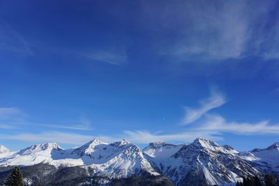 Scenic view of snowcapped mountains against blue sky