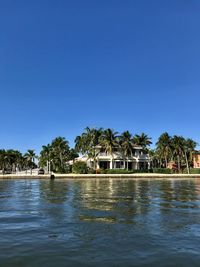 Swimming pool by lake against clear blue sky