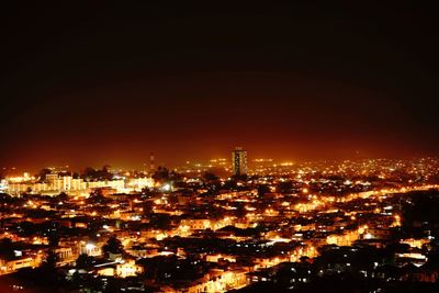 Illuminated cityscape against sky at night