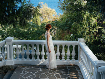 Woman standing by railing against trees