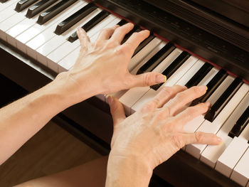 High angle view of hands playing piano