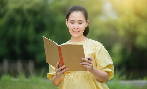 Portrait of a smiling young woman reading book