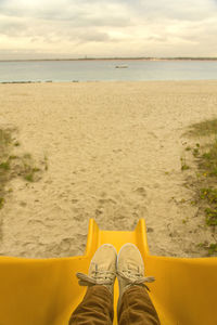 Low section of man on yellow slide at beach