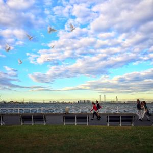 People on the road against cloudy sky