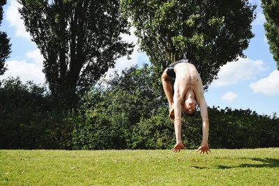 Man backflipping on grassy field against trees