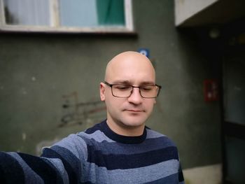 Man wearing eyeglasses standing against wall of building