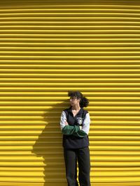 High angle view of young woman standing against yellow wall