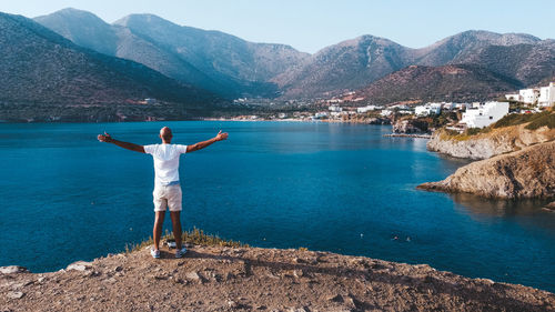 Rear view of woman standing by lake